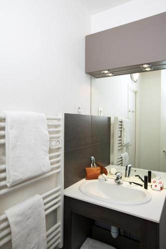 a bathroom with a sink and a mirror at Séjours & Affaires Courbevoie Grande Arche in Courbevoie
