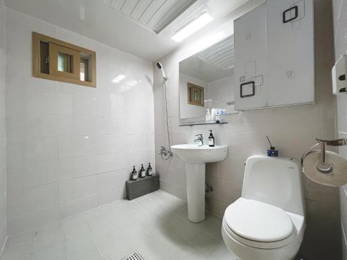 a white bathroom with a toilet and a sink at Modern K-style House in Seoul
