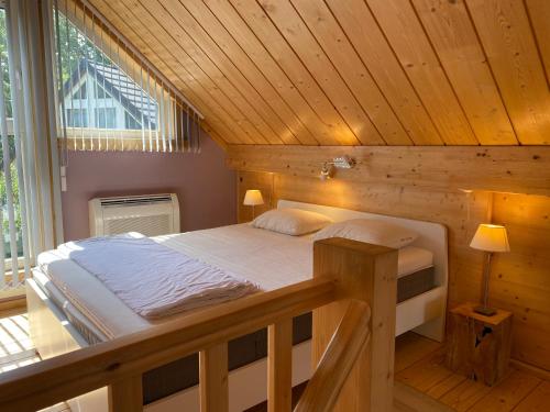a bedroom with a bed in a wooden room at L'écureuil des Lacs-4 pers in Froid-Chapelle