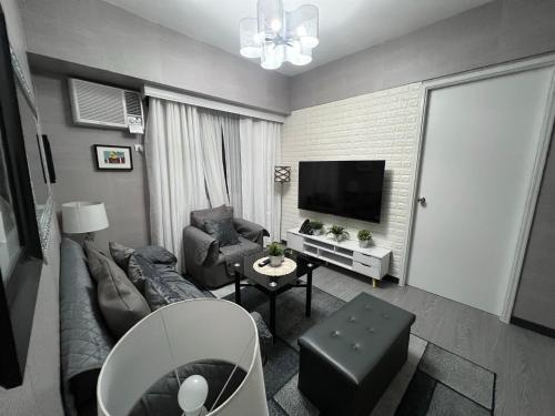 a living room with a couch and a tv at Spacious 2 Bedroom condo unit for rent in Iloilo City
