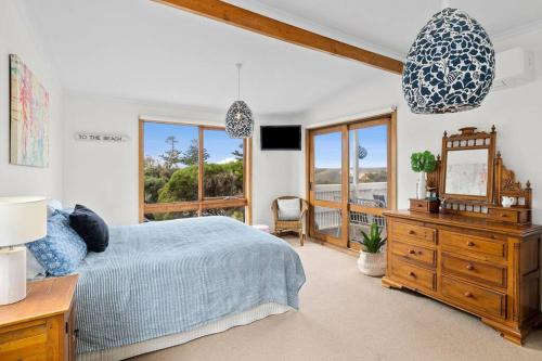 a bedroom with a bed and a dresser with a mirror at Two houses from the beach 100m to Sand and Surf Sea Views in Torquay