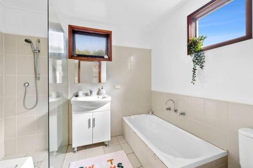 a bathroom with a sink and a tub and a shower at Two houses from the beach 100m to Sand and Surf Sea Views in Torquay