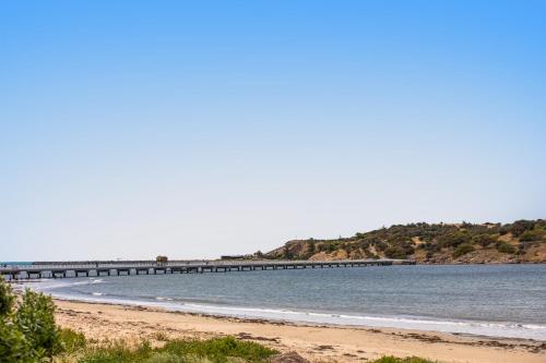 a beach with a pier in the water at Nightcap at Hotel Victor in Victor Harbor