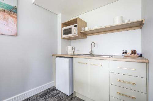 a white kitchen with a sink and a microwave at Nightcap at Hotel Victor in Victor Harbor