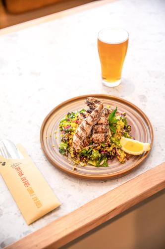 a plate of food on a table with a glass of beer at Nightcap at Hotel Victor in Victor Harbor