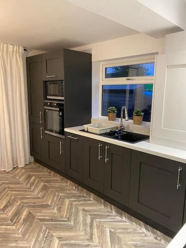 a kitchen with black cabinets and a sink and a window at Wharfedale Lodge- Bungalow-3 Bed, 2 bath, Amazing! in Thornton