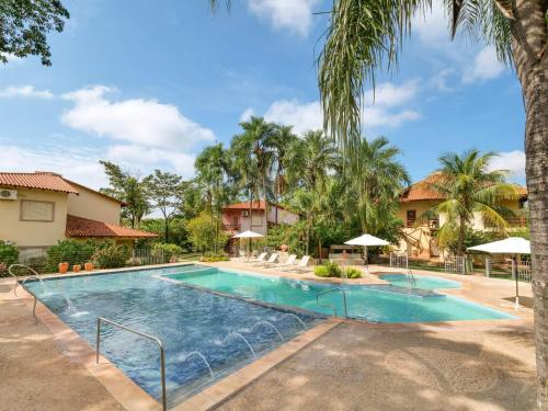 a swimming pool in a resort with palm trees at Hotel Pousada Águas de Bonito in Bonito
