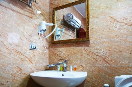 a bathroom with a sink and a mirror and a camera at Moonlight Hotel Addis Ababa in Addis Ababa