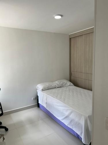 a bedroom with a bed in a white room at Espectacular apartamento en Condominio con BBQ in Ricaurte