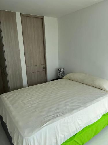a bedroom with a large white bed with a door at Espectacular apartamento en Condominio con BBQ in Ricaurte