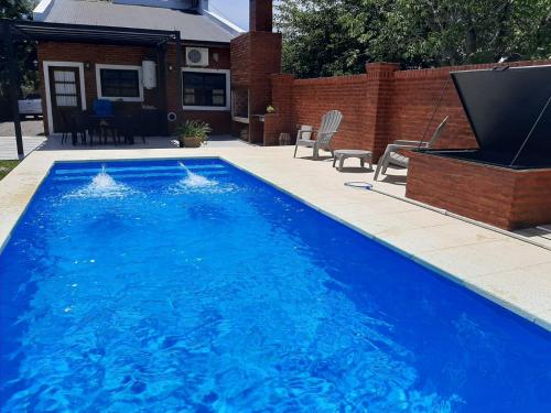 una gran piscina azul junto a una casa en Un Lugar Encantador - Chalet con Hermoso Parque, Pileta y Solárium en Open Door