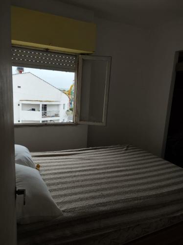 1 dormitorio con cama y ventana en Edificio Barracuda en Santa Teresita