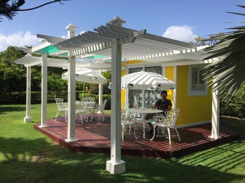 a man sitting at a table under a white pergola at HOTEL CASA AMARILLA et RESTAURANT in Punta Chame