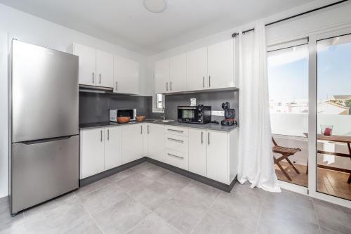 cocina con armarios blancos y nevera de acero inoxidable en Luxury Beach Apartments Diama, en Playa Honda