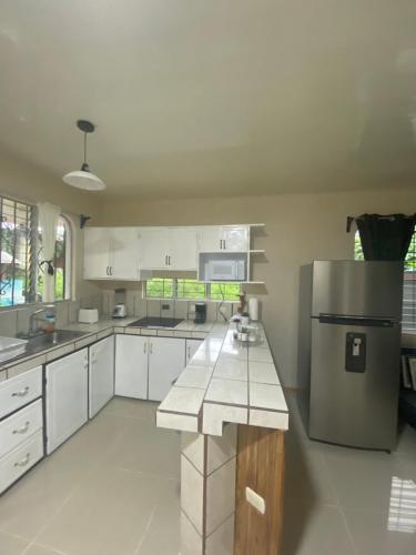 a kitchen with white cabinets and a stainless steel refrigerator at Agutí Apartment in Manuel Antonio