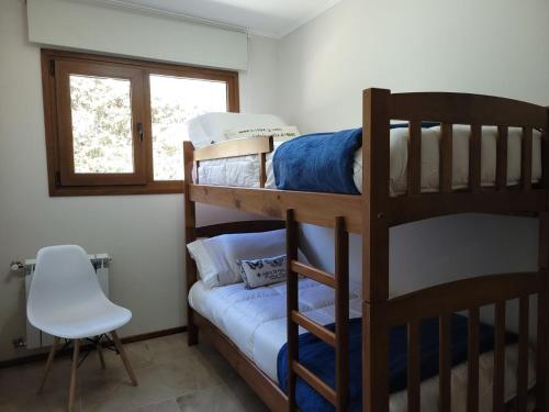 a bedroom with two bunk beds and a chair at Aires del Sur in Dina Huapi