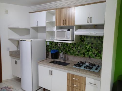 a kitchen with white cabinets and a sink and a microwave at B101 AP do Lago, com Cozinha e Churrasqueira privativa , internet banda larga, rampa barco e jet, pesqueiro in Caldas Novas