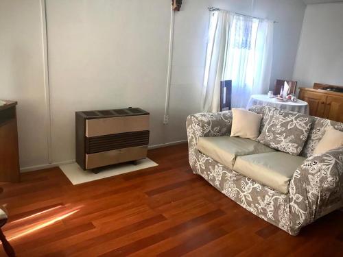 a living room with a couch and a wooden floor at Cabañas Esmeralda con Desayuno in Punta Arenas