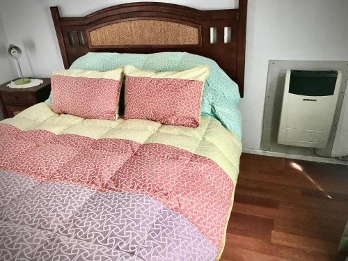 a bedroom with a bed with pillows and a tv at Cabañas Esmeralda con Desayuno in Punta Arenas