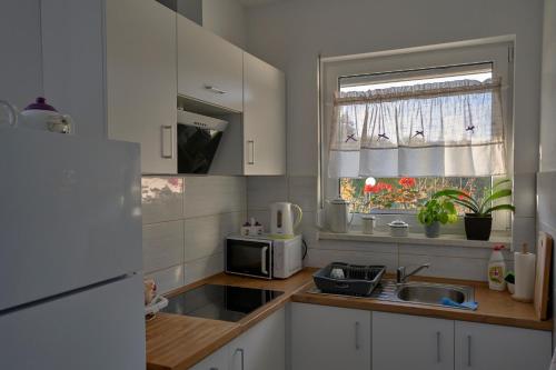 a kitchen with white cabinets and a sink and a window at Pensjonat Na Każdą Porę in Lądek-Zdrój