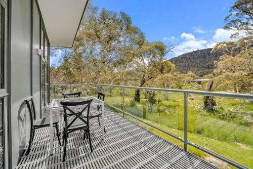 a balcony with a table and chairs and a view at Ecocrackenback 13 Sustainable chalet. Stay 3, Pay 2 Summer 2026 in Crackenback