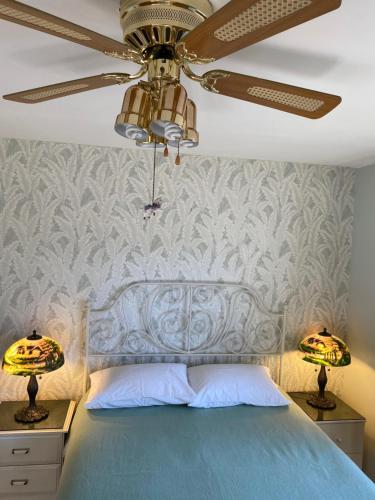 1 dormitorio con 1 cama azul y ventilador de techo en Serenity en Burnaby