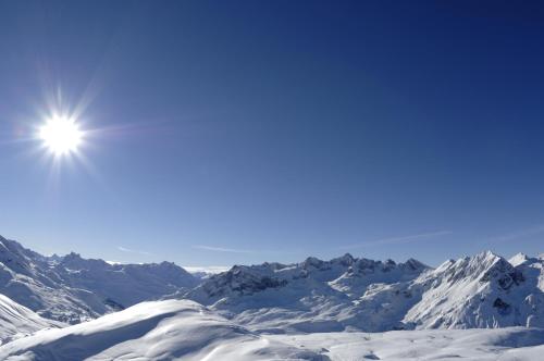 a snow covered mountain range with the sun in the sky at Haus Anna Apartments in Langen am Arlberg
