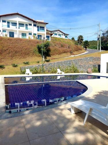 a white bench sitting next to a swimming pool at Suíte no Mirante em Escarpas in Capitólio