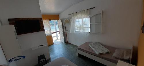 Habitación pequeña con cama y TV. en Pousada da Ponte en Praia de Araçatiba
