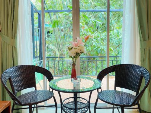 a table with two chairs and a vase with flowers on it at Phuket Jungle Experience Resort in Karon Beach