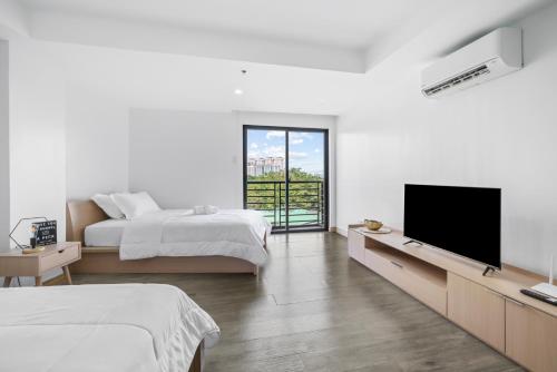 a white bedroom with two beds and a flat screen tv at Espacio Hotel in Manila