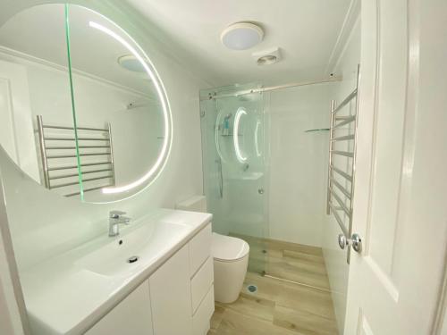 Luxury Manly Beachfront Apartment في سيدني: حمام أبيض مع حوض ودش