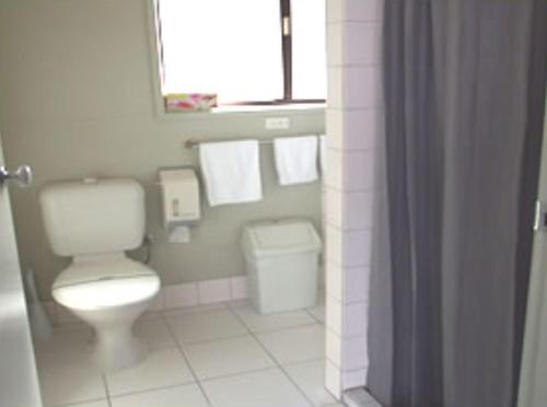 a bathroom with a toilet and a window and towels at Abbotswood Motor Inn in Geelong