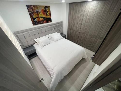 Aparta estudio central con ascensor 403 في بوغوتا: غرفة نوم صغيرة مع سرير أبيض وخزانة