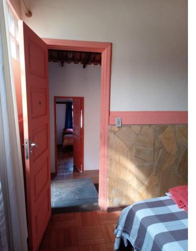 a bedroom with a bed and a red door at Pouso do Elefante in Serra do Cipo