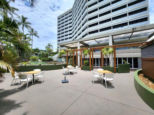 a patio with tables and chairs in front of a building at Cairns Ocean View Apartment in Cairns