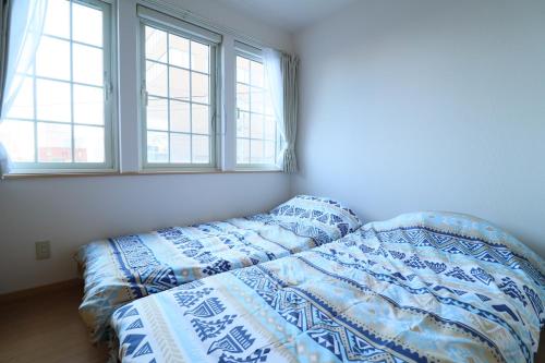 sypialnia z łóżkiem i 2 oknami w obiekcie pier21 w mieście Hakodate