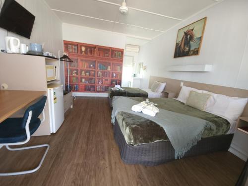 a hotel room with two beds and a desk at Charters Towers Motel in Charters Towers