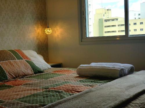 a bed with a blanket on it in a room with a window at Apê Novo em Sampa Prox do Tietê Plaza in Sao Paulo
