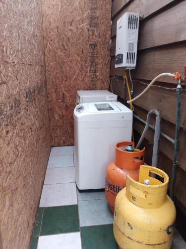 a small bathroom with a washing machine and buckets at Cabañas Roka Caburgua in Pucón