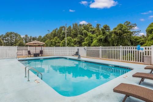 einen Pool mit zwei Stühlen und einem Zaun in der Unterkunft Hometown Inn Thomasville in Thomasville