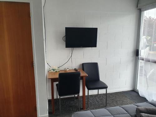 a dining room table with two chairs and a television on a wall at Brooklyne Motel Sanson in Sanson