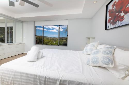 a white bedroom with a large bed and a window at Marine Drive in Forster
