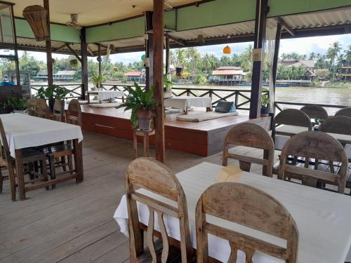 um restaurante com mesas e cadeiras num barco em Rivergarden Guesthouse and restaurant em Don Det