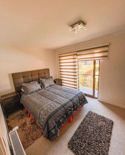 Un dormitorio con una cama y una ventana grande. en Casa Alicura Pucon, en Pucón