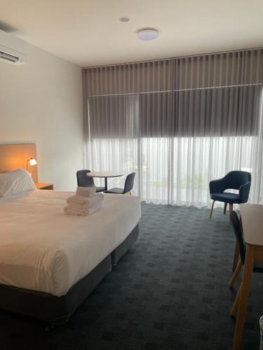 a hotel room with a bed and chairs and a window at Whittlesea Motel in Whittlesea