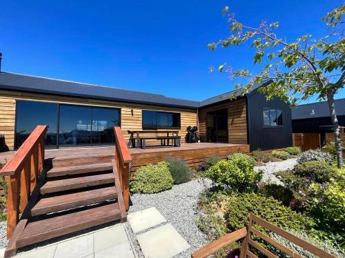 a house with a wooden deck with a bench at Wayfarers Lodge in Lake Tekapo
