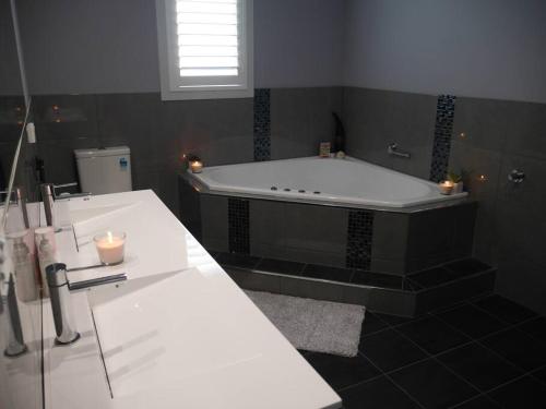 een badkamer met een bad met kaarsen en een wastafel bij Thirlmere Stayz 4 Bedroom Home with Spa in Thirlmere