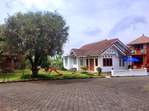 ein weißes Haus mit einem Baum und einer Auffahrt in der Unterkunft Villa Gazebo Galaxy in Cianjur