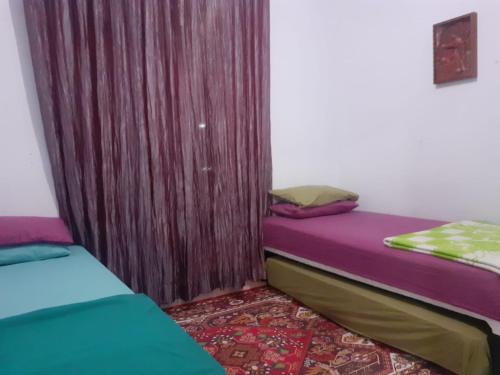 2 Betten in einem Zimmer mit lila Vorhängen in der Unterkunft Villa Gazebo Galaxy in Cianjur